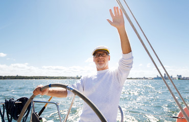 senior man at helm on boat or yacht sailing in sea