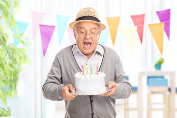 Delighted senior blowing candles on a cake