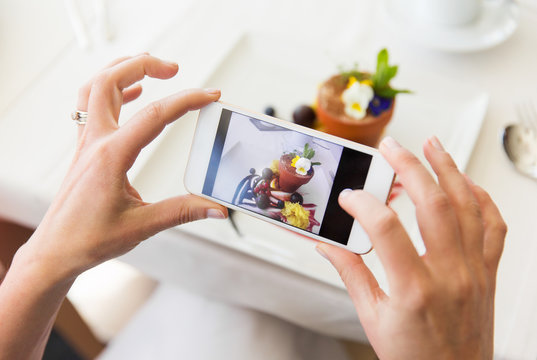 close up of woman picturing food by smartphone