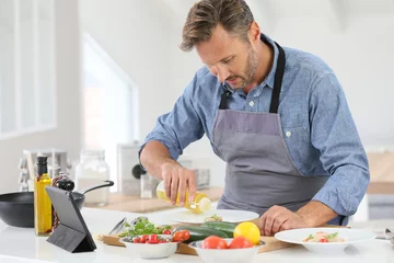 Fotobehang Koken Man in keuken kookschotel en met behulp van digitale tablet