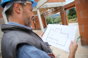 Construction manager checking blueprint on site