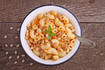 pasta with meat and beans in a white bowl on the old wooden background