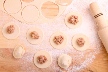 dumplings(pelmeni) with meat on a light wooden background