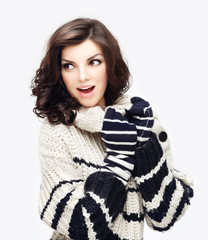 Winter portrait of a beautiful young woman wearing sweater posing against blue background and smiling