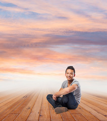 Fototapeta na wymiar young asian man sitting on a wooden floor in front of a late aft
