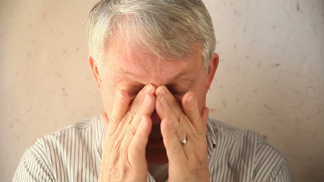 An older man tries to relieve the pain around his eyes.