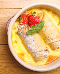rolled pancakes on a plate with honey and powdered sugar