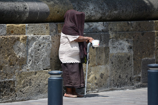 Señora pide monedas en la calle y esconde su rostro.