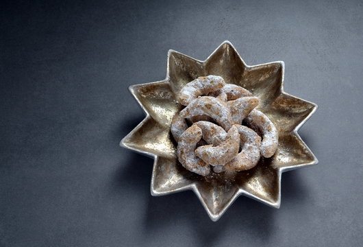 German Kipferl Cookies dusted with icing sugar on a star shaped plate against a grey background 7