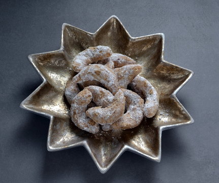 German Kipferl Cookies dusted with icing sugar on a star shaped plate against a grey background 6