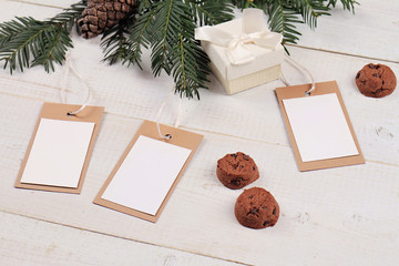 Fototapeta na wymiar Christmas and New Year background. Christmas blank presents tags, decoration, fir branch and cookies on white wooden background. Copy space image