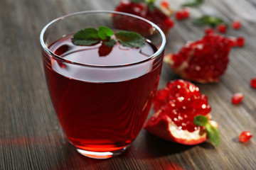 A glass of tasty juice and garnet fruit, on wooden background