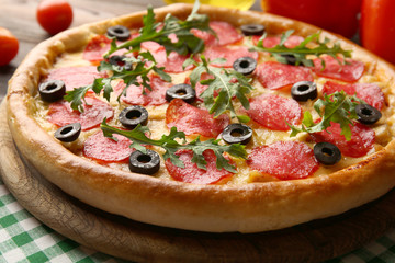Tasty pizza with salami on decorated wooden table