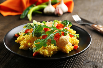Black plate with vegetable risotto on served wooden table