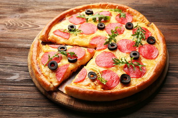Hot tasty pizza with salami and olives on wooden background