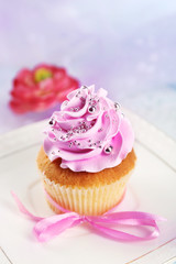 Cake with sugar paste flowers and cupcakes, on light background