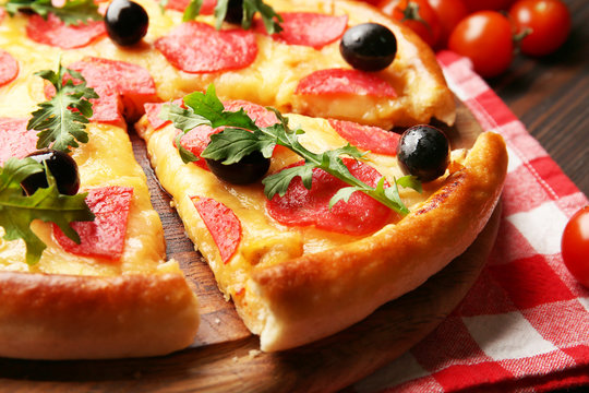 Delicious tasty pizza with salami and olives on wooden background, close up