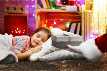 Obraz premium Pretty little girl laying on the pillow under soft plaid waiting for Santa's gift in Christmas decorated room