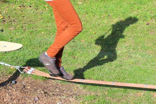 Schatten einer Frau beim Slacklinen in einem Park
