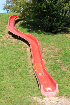 Eine rote Halbschalenrutsche auf einem Abenteuerspielplatz