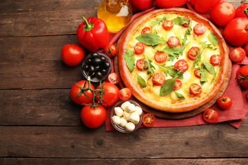 Pizza Margherita with arugula and vegetables on wooden table