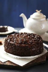 Tasty chocolate cake on color wooden background