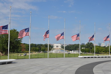 Opuszczone do połowy powiewające amerykańskie flagi na tle National Mall w Waszyngtonie - obrazy, fototapety, plakaty