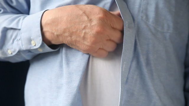 A businessman scratches a persistent itch on his torso.