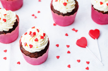 cupcake with cream cheese frosting and heart sprinkles and the c