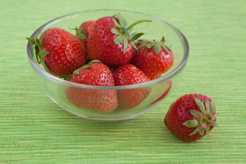 strawberries in a glass bowl on the tablecloth