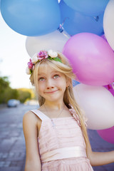 Little five-year girl in a pink dress holding balloons