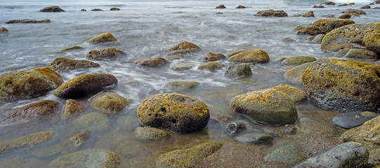 Slow waves on a rocky beach in summer