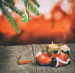 Pine branch with Christmas tree toy, ceramic candle holder on old wood table.
Cross processed image for vintage look