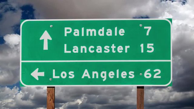 Los Angeles, Palmdale and Lancaster highway sign with time lapse clouds.