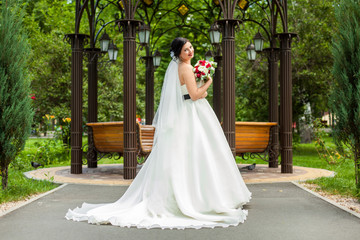 Fototapeta premium Bride with bouquet near wooden pavilion