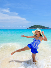 Beautiful woman in a blue white striped swimsuit standing with gestures have fun and happy under summer sky on the beach of Koh Miang Island in Mu Ko Similan National Park, Phang Nga, Thailand