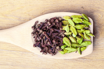cardamom pods and cloves on wooden spoon