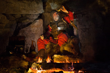 Medieval King in armor is looking at the empty cup of wine