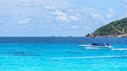 Fototapeta na wymiar White speed boat was running slowly on the blue sea surface in front of Koh Miang Island under the summer sky and beautiful nature in Mu Ko Similan National Park, Phang Nga, Thailand, 16:9 wide screen