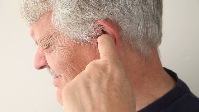 An older man suffering from pain deep in his ear