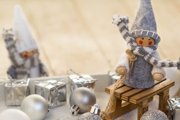 Christmas composition with ornaments, gift box and cute gnomes on wooden sled.