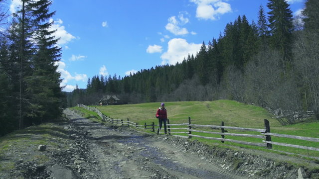 female hiker walking along the fence of an old farm in forest