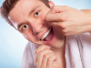 Young man cleaning her white teeth with dental floss