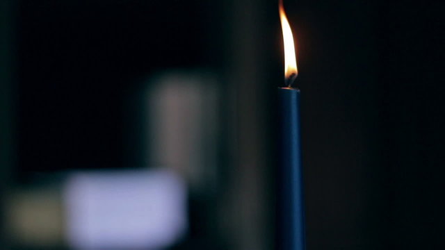 Closeup of a blue burning candle flickering and being blown out