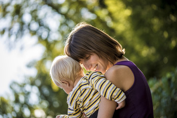 Content young mother carrying and hugging her baby boy