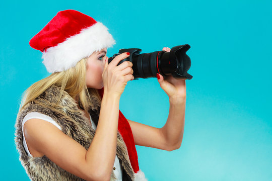 Photographer girl in santa claus hat shooting images
