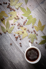 cup of coffee and coffee bean and dry leaves on Wooden Table