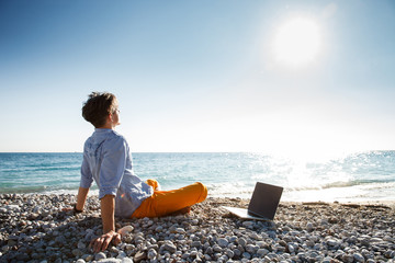 Man walking with laptop computer by the sea coast