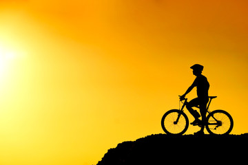 Obraz premium A cyclist on the hill with sunset silhouette
