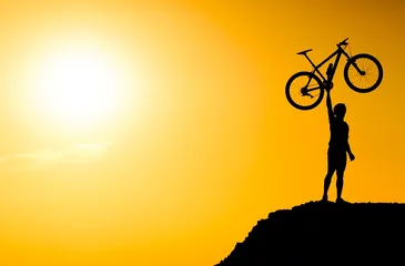 Papier Peint photo autocollant Vélo silhouette d& 39 un cycliste de vélo de montagne debout sur la montagne levant son vélo